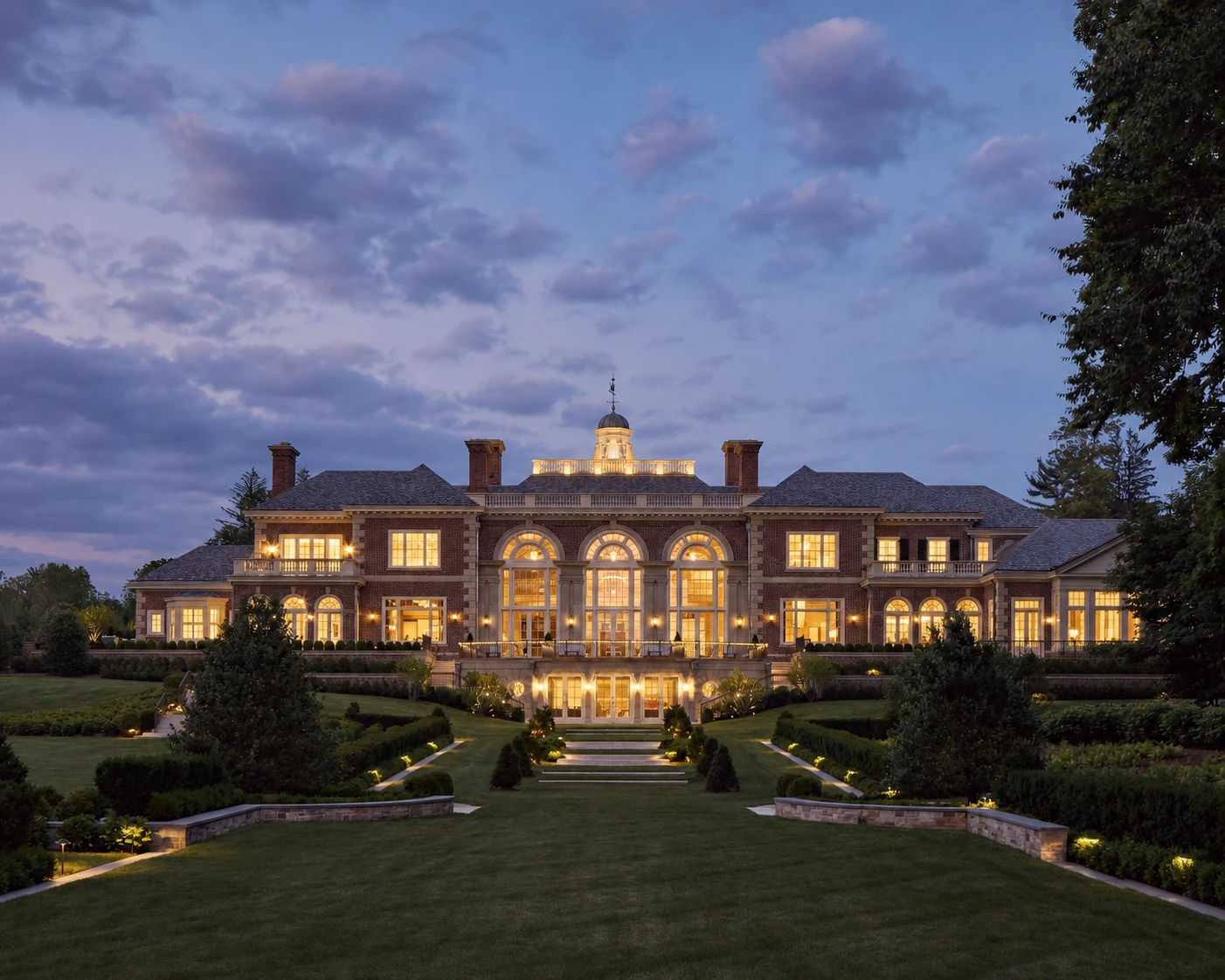 Mid Country Grandeur illuminated garden facade at dusk in Fairfield County, Connecticut, built by Hobbs Inc.